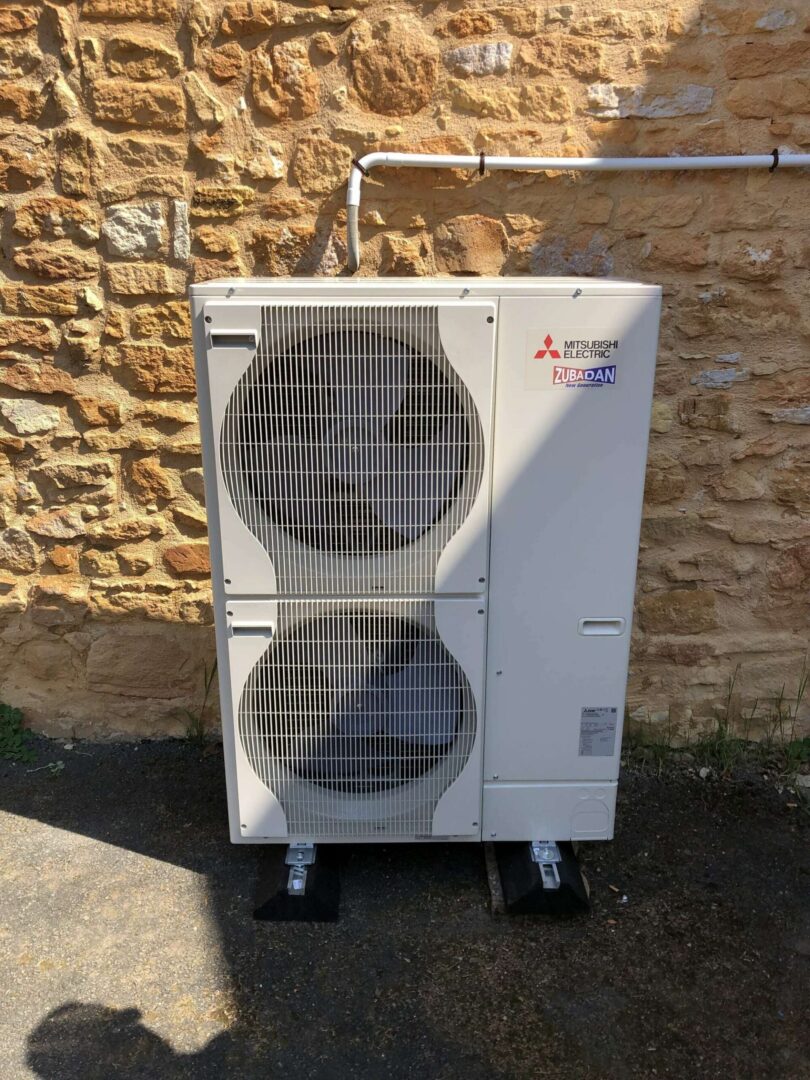 Pompe à chaleur air/eau — PAC air/eau — unité extérieure sur mur pierre, réalisation Protec Energy en Rhône-Alpes