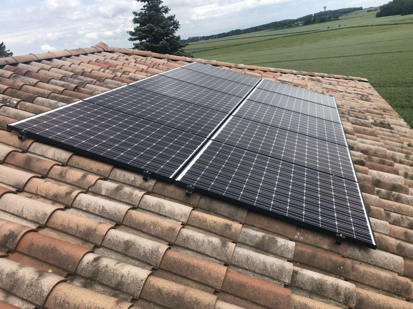 Installation photovoltaïque — Toiture tuiles, champ en fond, réalisation Protec Energy en Rhône-Alpes